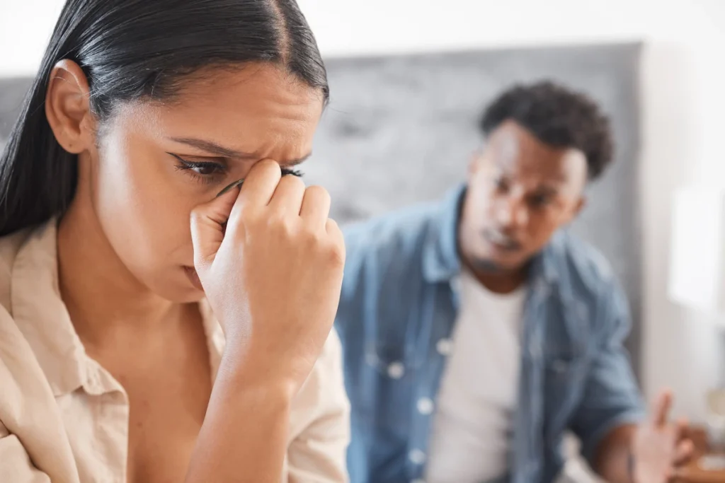 Une femme qui se tient la tête en écoutant un homme à l'arrière