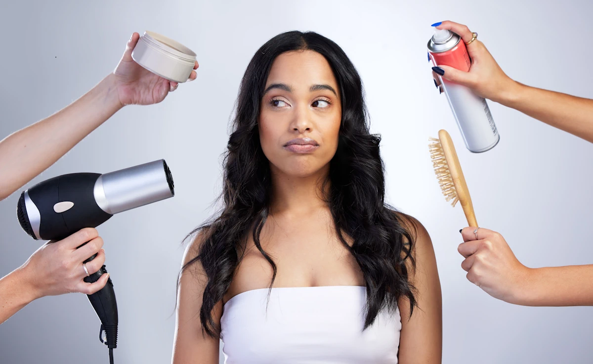 Une femme entouré de plusieurs mains qui tient chacun des produits de soins pour les cheveux