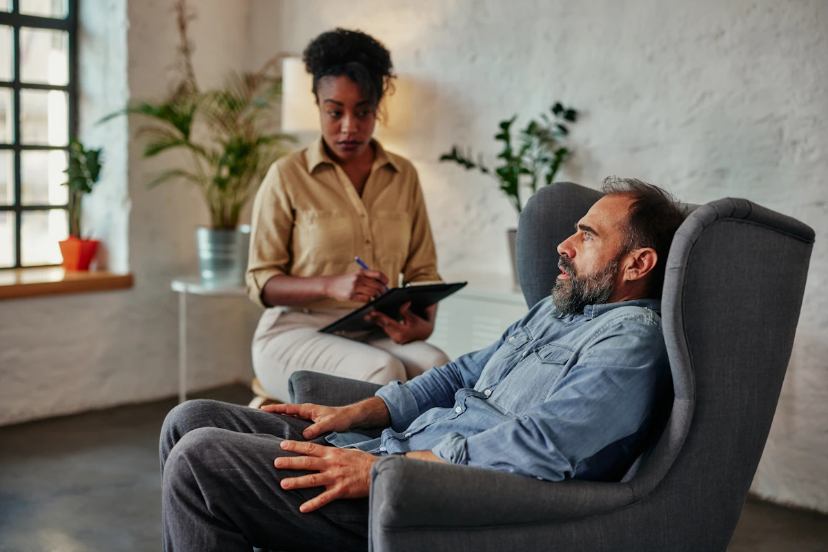 Un homme assis dans un fauteuil qui consulte une thérapeute