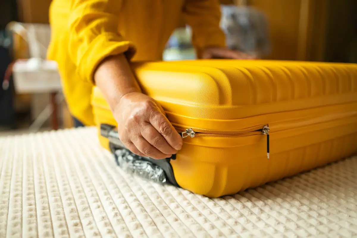 Une femme qui prépare une valise jaune