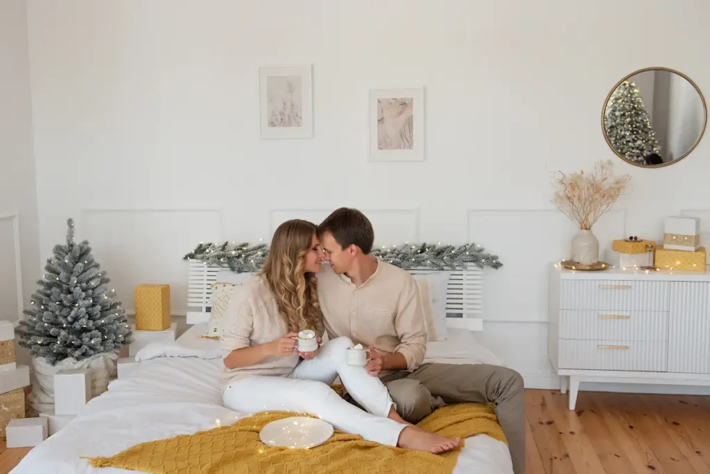 Un couple sur un lit entouré de feuillages illuminé et de quelques meubles