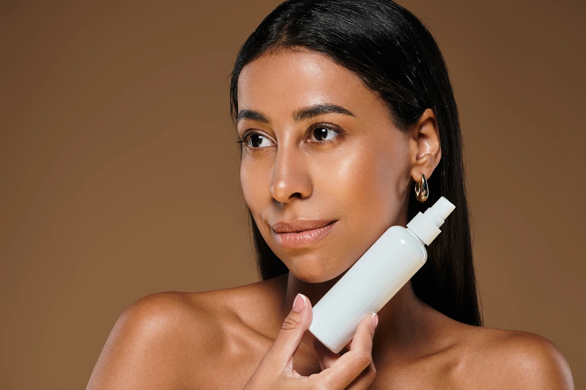 Une femme légèrement bronzée qui tient un produit contre son visage