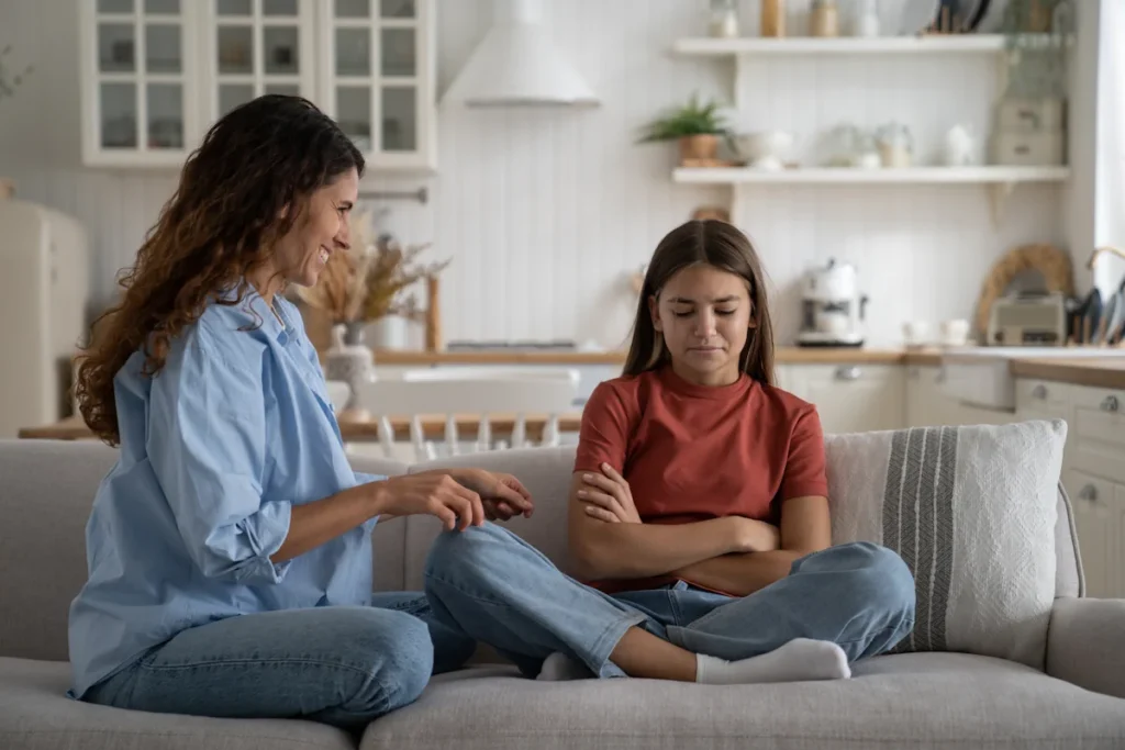 Une femme et une ado sur un canapé qui essaie de discuter