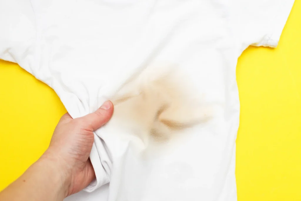 Une personne qui tient un T-shirt blanc avec une tache marron