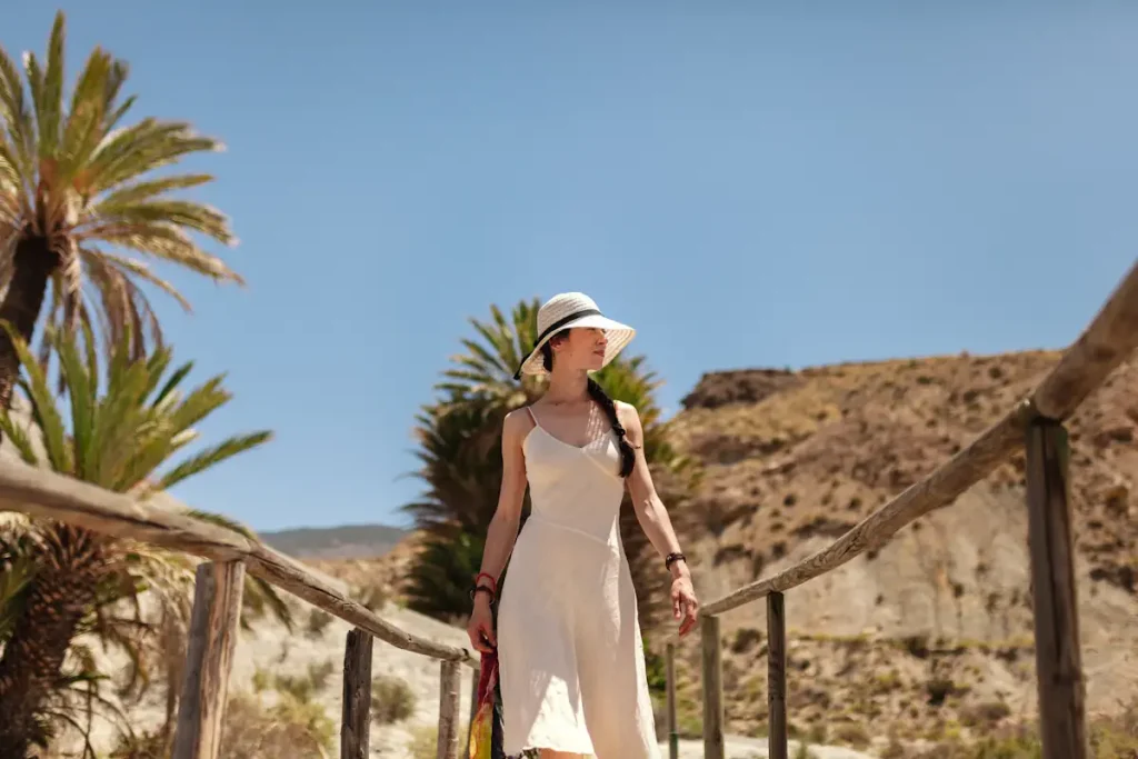Une femme en robe blanche avec un chapeau qui se promène