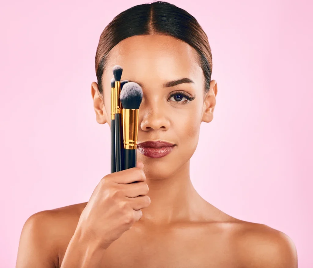 Une femme qui tient plusieurs pinceaux pour cacher son œil