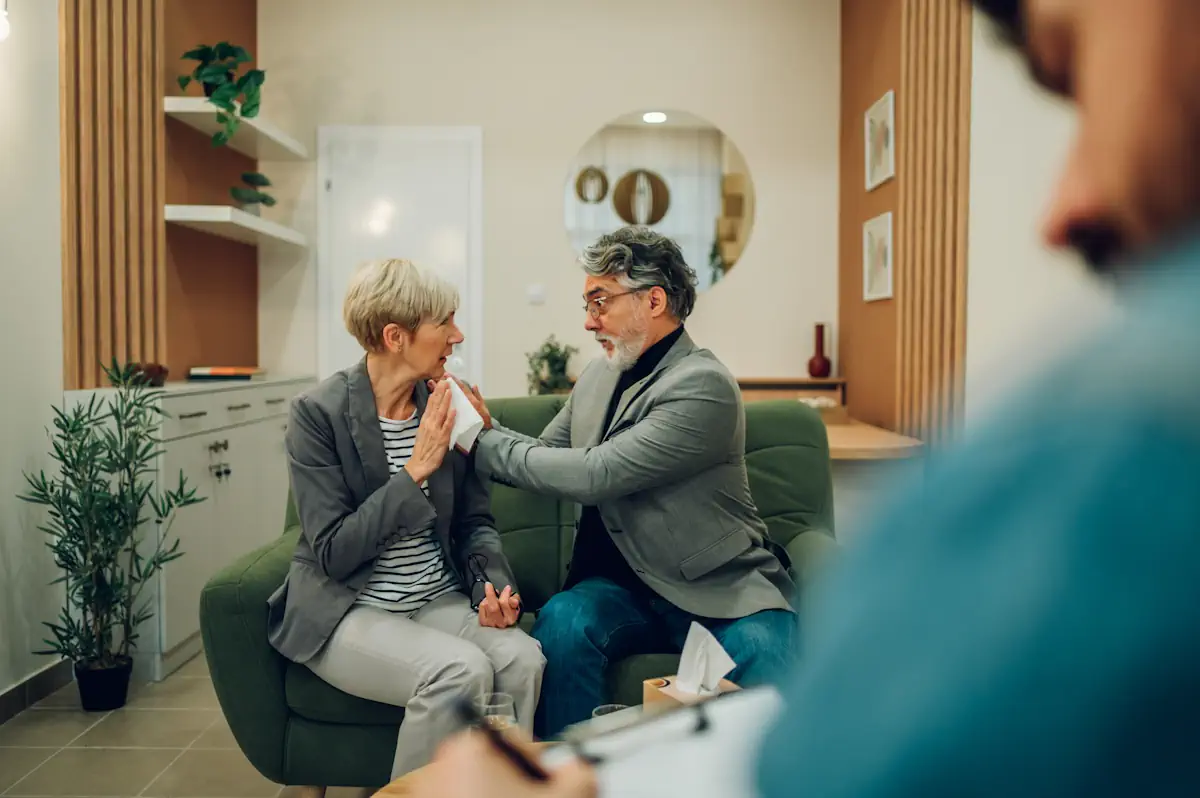 Un couple de sénior qui discute sur un canapé face à un homme
