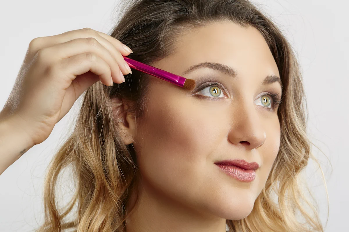 Une femme qui se maquille les yeux avec un pinceau plat