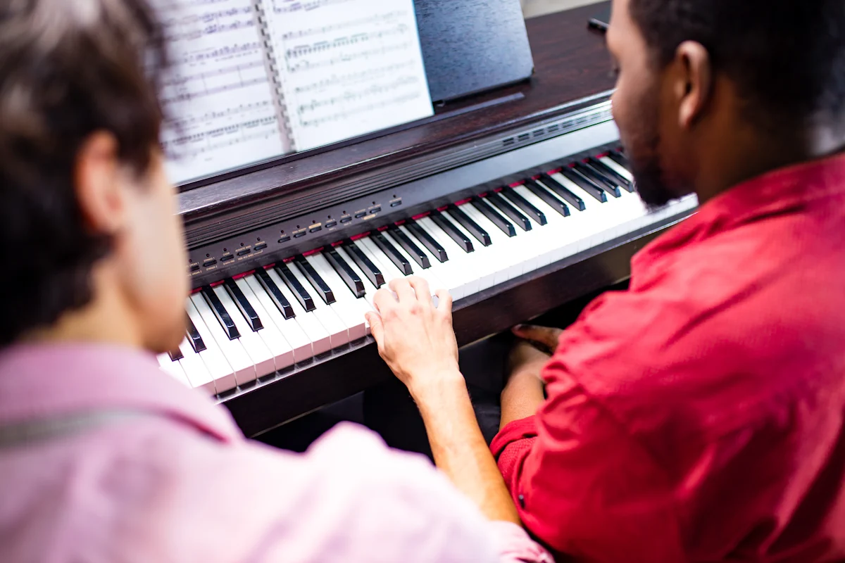 Un homme qui apprend le piano sous le regard d'un autre