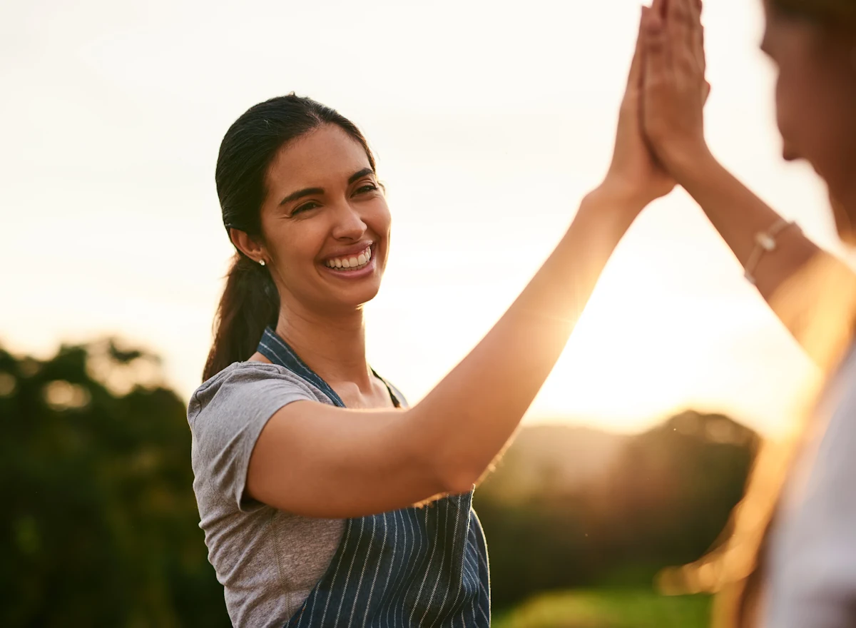 Une femme souriante qui tape dans la main d'une autre personne