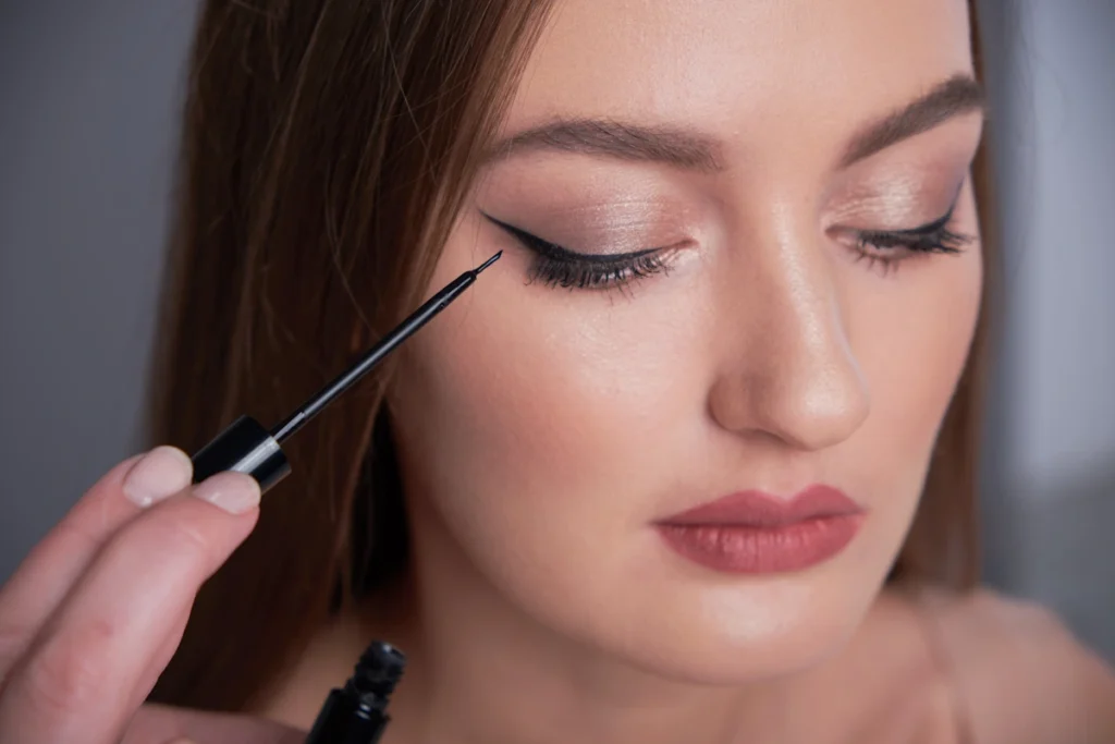 Une femme avec les yeux sensibles qui applique de l'eye- liner