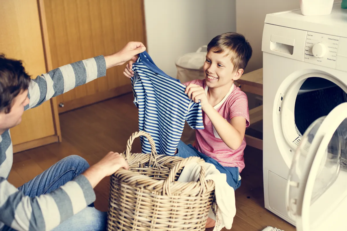 Un enfant avec son papa qui fait une lessive