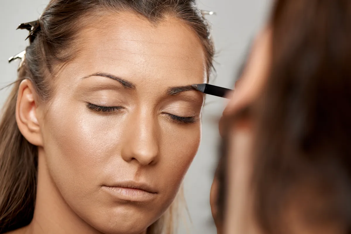 Une femme qui maquille des sourcils asymétriques