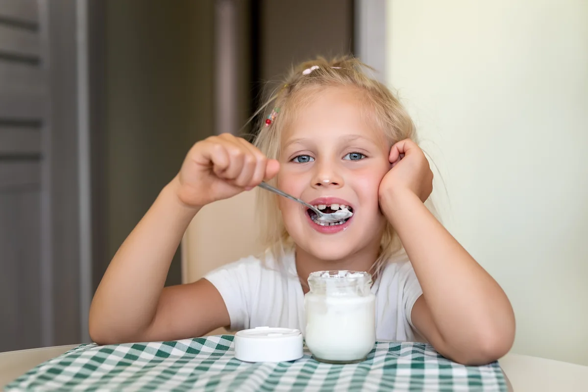 Un enfant qui mange un yaourt au petit déjeuner